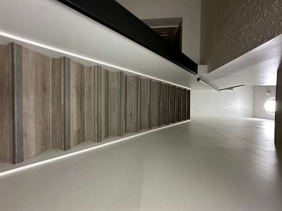 A long hallway with a white ceiling and a wall with wood paneling.