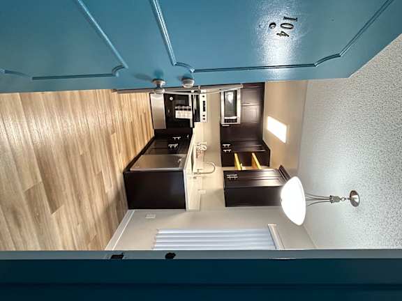 A compact, fully upgraded kitchen in a modern studio apartment, featuring sleek countertops, stainless steel appliances, and ample storage space
