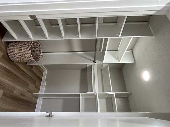 a walk in closet with built in white shelves and a basket in it and a shoe shelf