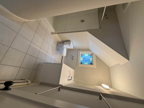 A bathroom with a stained glass window in the shower.