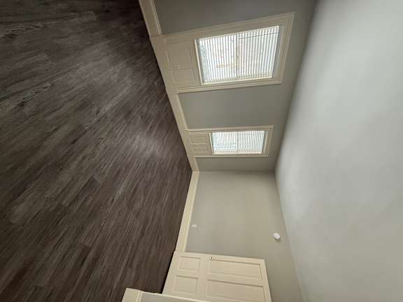 A room with a dark wood floor and a white ceiling with two skylights.