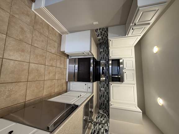A kitchen with a microwave, oven, and sink.