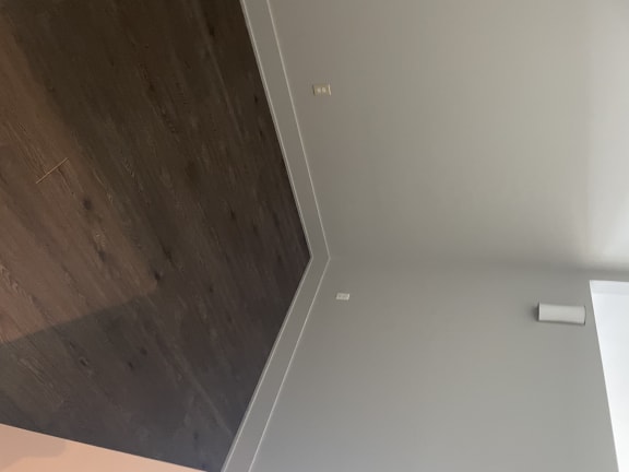 a corner of a room with grey walls and a wooden floor