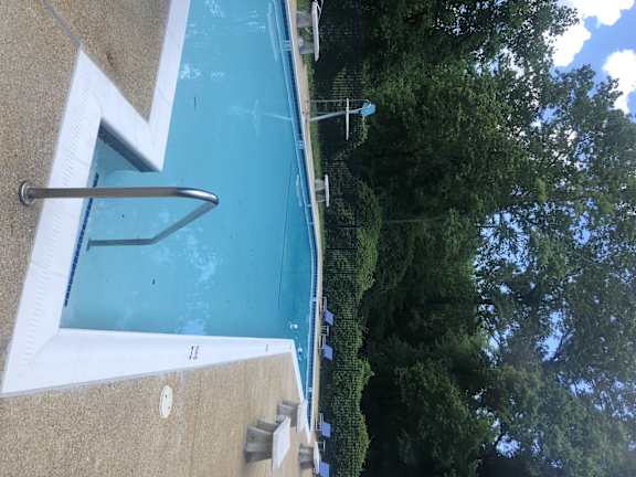 A pool with a diving board and a metal ladder.