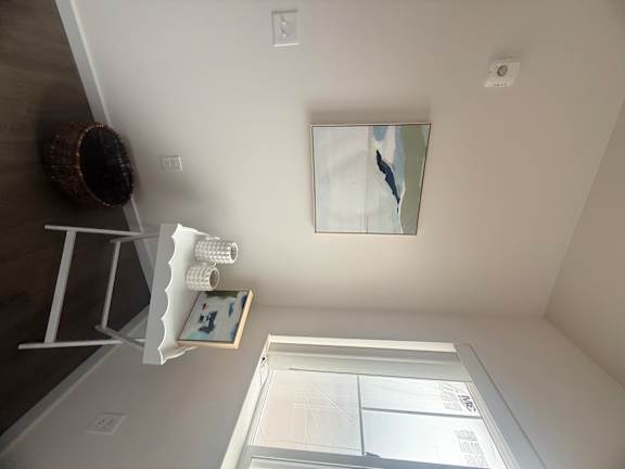 A mirror hangs on a wall above a shelf.