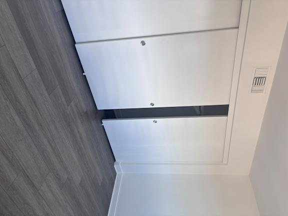 Fully-Furnished Townhomes in Corona, CA - Dos Lagos Townhomes - Closet With White Sliding Doors, Gray Wood-Style Flooring, Neutral Walls, Baseboard Trim, And An Overhead Air Vent.