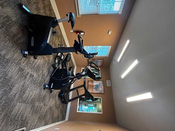 A room with exercise bikes and a window with blinds.