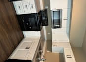 Thumbnail 34 of 48 - A modern kitchen with black and white appliances and wooden flooring.