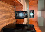 Thumbnail 46 of 48 - A kitchen with wooden cabinets and a black countertop.