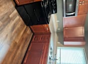 Thumbnail 29 of 48 - A kitchen with wooden cabinets and black appliances.