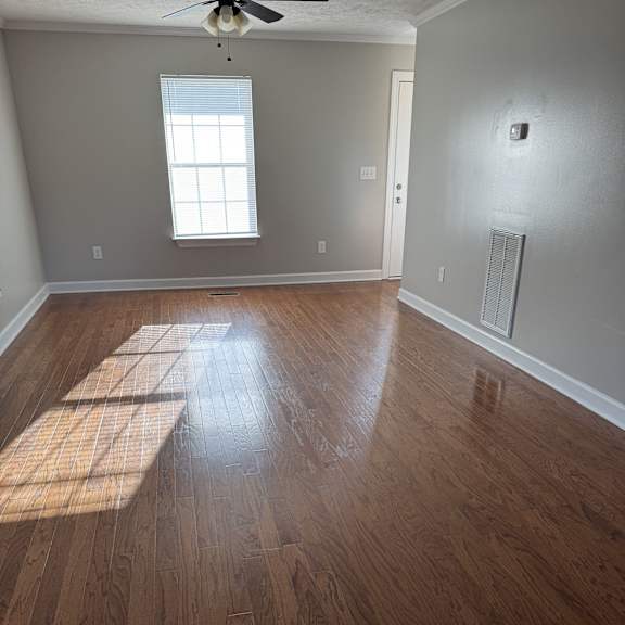 A room with wooden floors and a window letting in sunlight.
