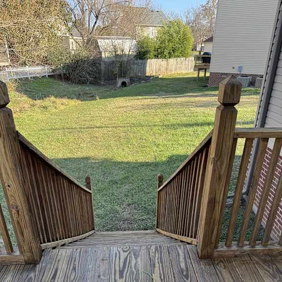 A wooden deck with a metal roof and a grassy area in the background.