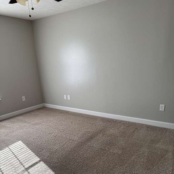 A room with a carpeted floor and a wall with a window.