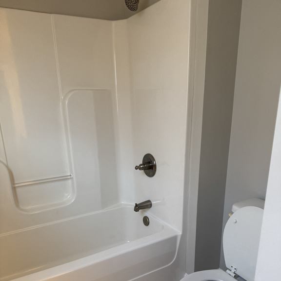 A white bathtub with a shower head and a shower hose.