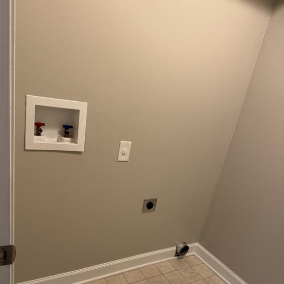 A bathroom with a tiled wall and a white door.