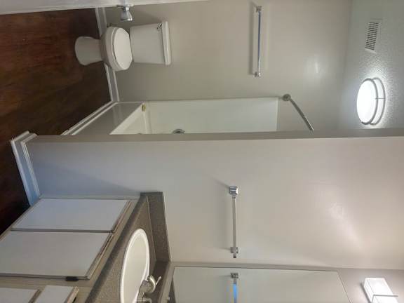 A white toilet with a silver flush handle is mounted on a white wall.