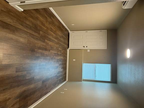 A room with a white door and a wooden wall.