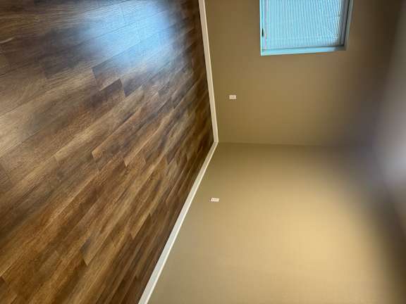 A wooden floor leads to a door.