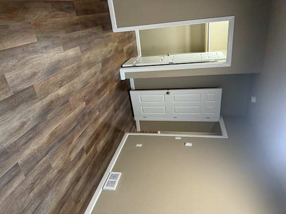 A white cabinet with a mirror above it is mounted on a wall with wood planks.