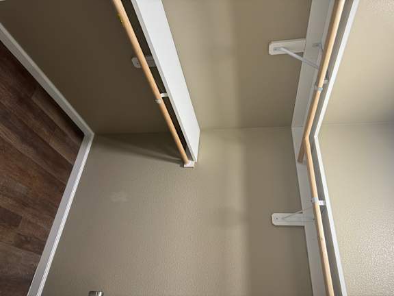 A white ladder with wooden handles is leaning against a wall.