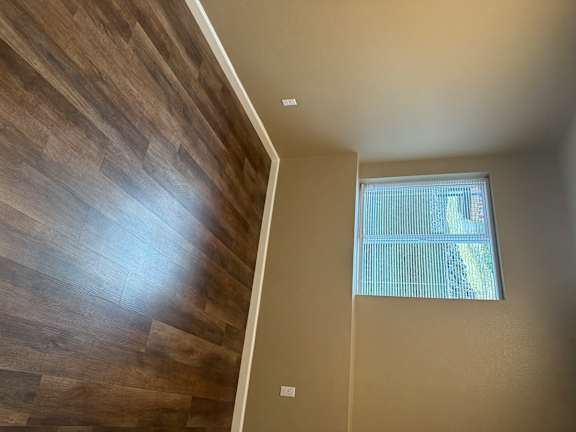 A room with a window and wooden flooring.