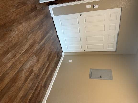 A white door in a room with wooden flooring.