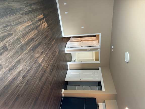 A modern kitchen with a wooden floor and white cabinets.