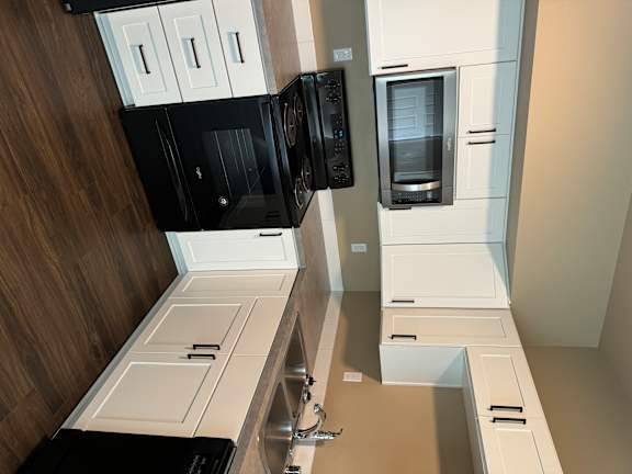 A modern kitchen with black and white appliances and wooden flooring.