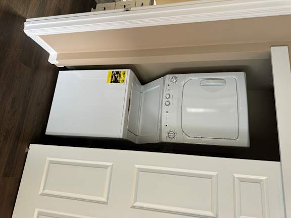 A white microwave oven is installed in a kitchen cabinet.