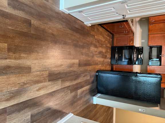 A kitchen with a black TV mounted above a white fridge.