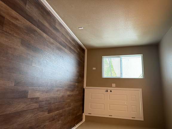 A room with a window and a wooden wall.