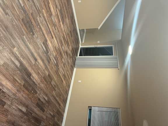 A staircase with a wooden floor and a wall with a window.