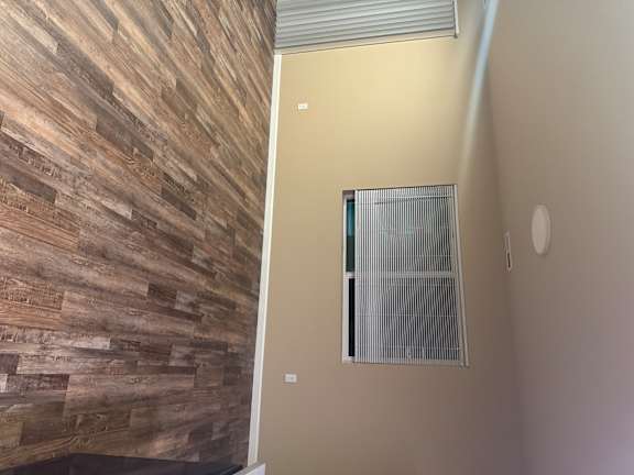 A room with a window and a wooden wall.