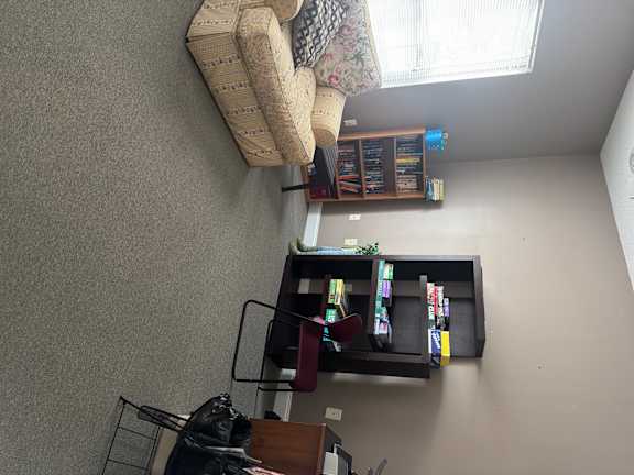 A living room with a couch, a television, and a window with blinds.