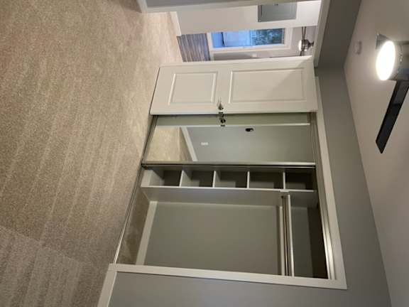 A white cabinet with a glass door is open.