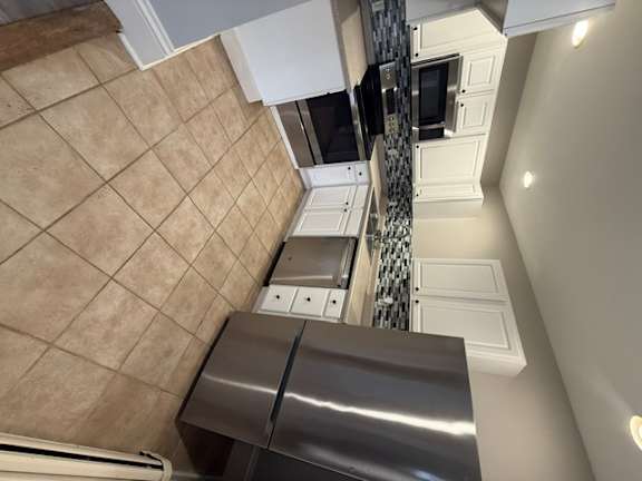A stainless steel refrigerator is installed in a kitchen.