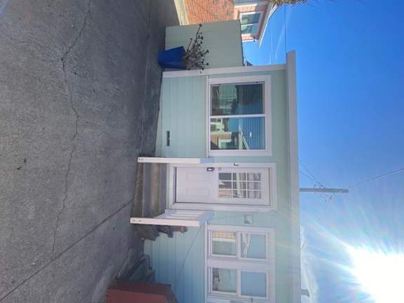 A white door is on the ground floor of a two-story house.