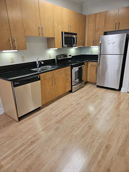 A modern kitchen with wooden cabinets and a black countertop.