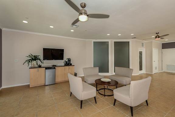 Seating area in club house with large TV and ceiling fan.