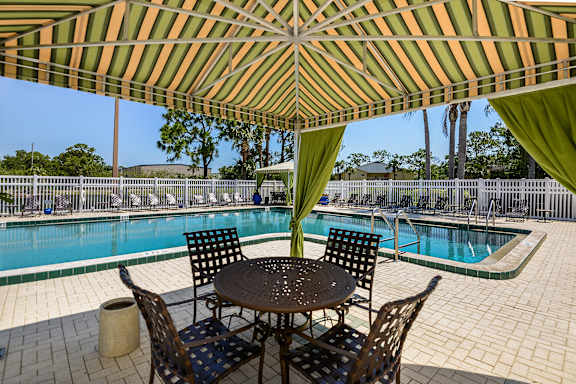 Cabaña with table and chairs underneath and the pool in the background.