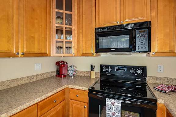 Wood style cabinets with stone like style counter tops and black appliances.