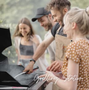 a group of people standing around a grill preparing food