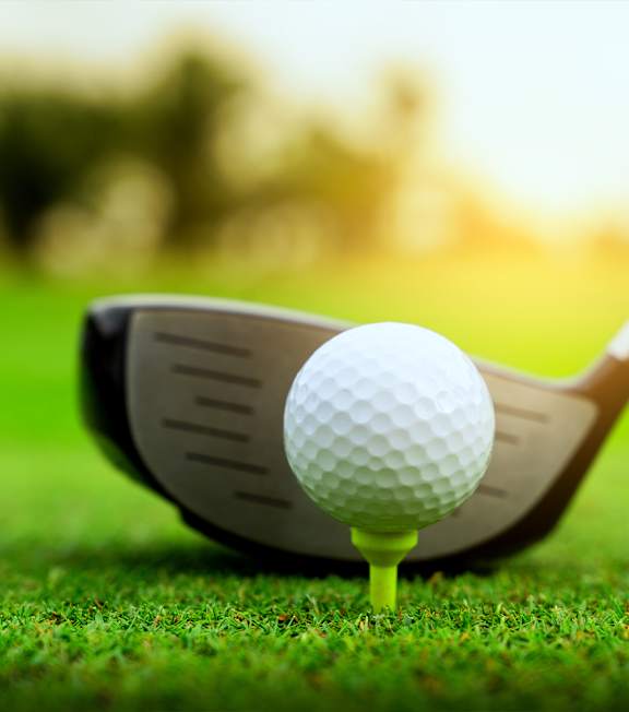A golf ball is placed on a tee next to a golf club.