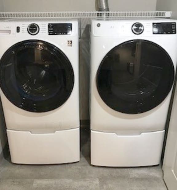 Two white front loading washing machines in a laundry room.