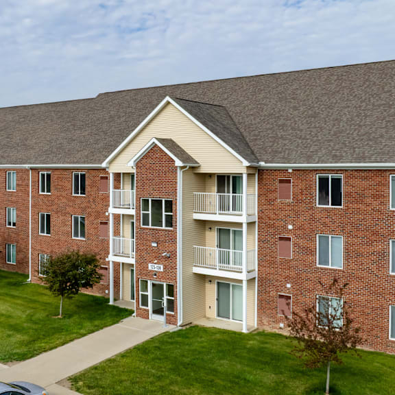 A red brick apartment building with a balcony on the second floor.