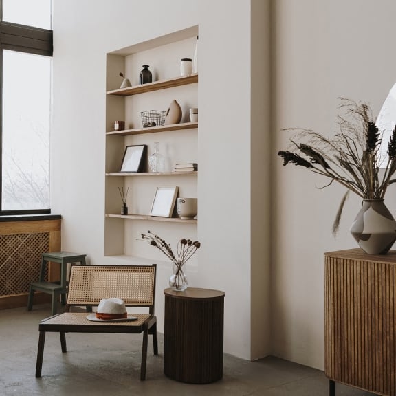a living room with a wicker chair and a table and a bookshelf