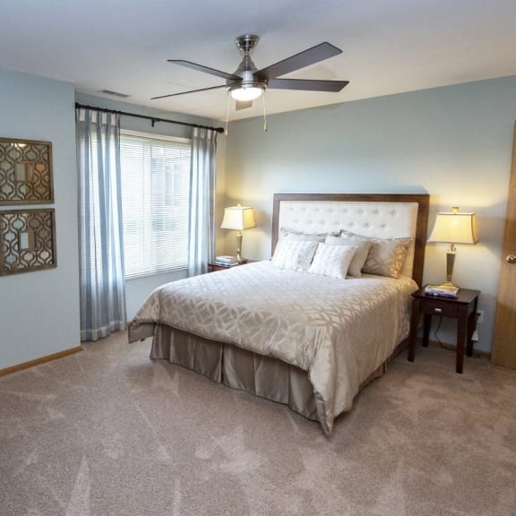 the master bedroom has a large bed and a ceiling fan
