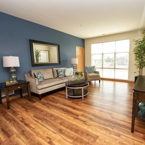 a living room with a blue accent wall and wooden floors