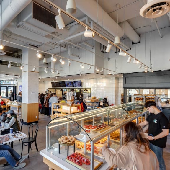 the interior of a bakery with people behind the display case at Southpark on Whyte, Edmonton