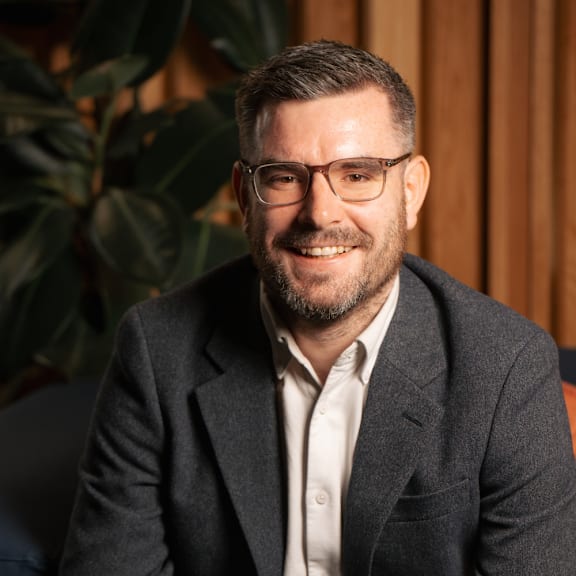 A man with glasses and a beard is smiling at the camera.
